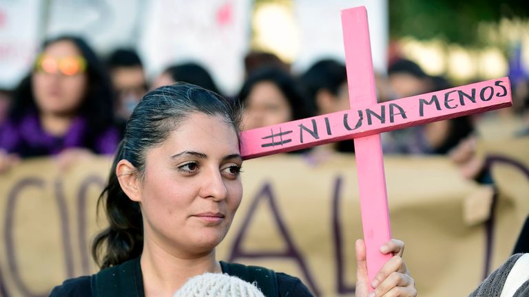 A woman with a baby holds a pink cross during a march in Mexico City 