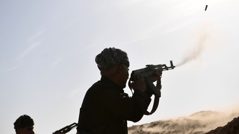 Kurdish Peshmerga fighters fire at an ISIS position during an assault to recapture the village of Tiskharab near Mosul, Iraq