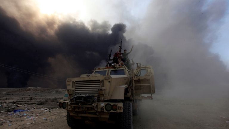 Iraqi army personnel ride on a military vehicle in Qayyarah