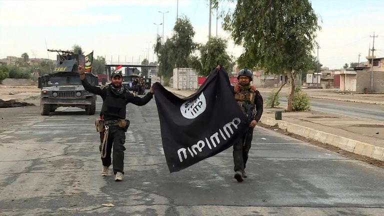 Two Iraqi soldiers carry a captured Islamic State flag