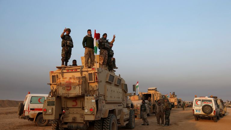 Peshmerga forces stand on a military vehicle in Bashiqa during an offensive against Islamic State