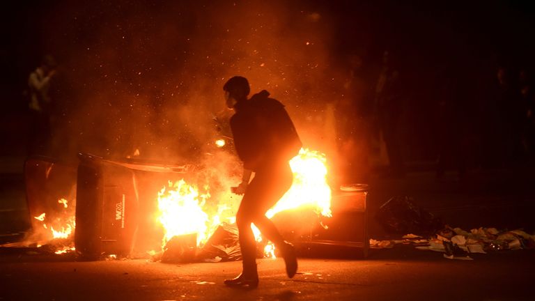 A woman passes burning garbage during a demonstration in Oakland, California, U.S. following the election of Donald Trump