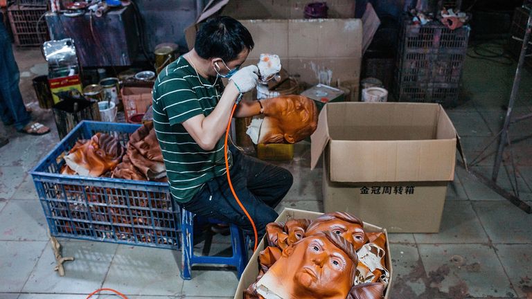 A worker paints a mask of Donald Trump's face in Shenzen, China