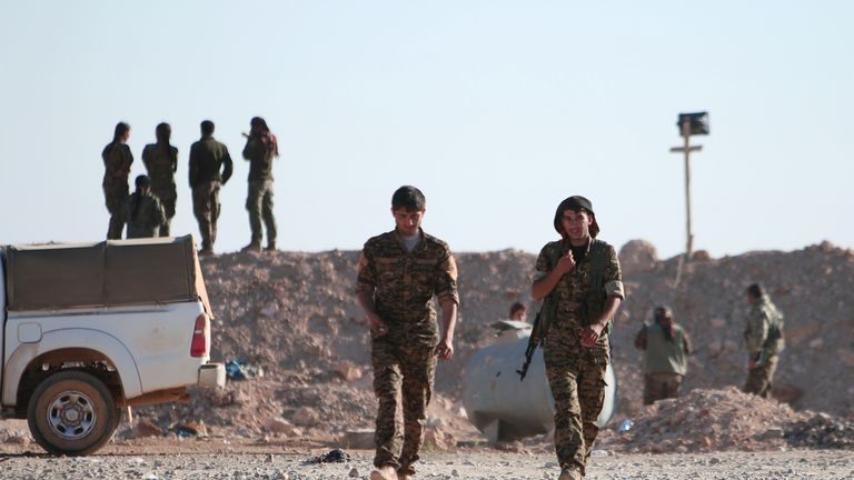 Syrian Democratic Forces (SDF) fighters walk with their weapons, north of Raqqa city