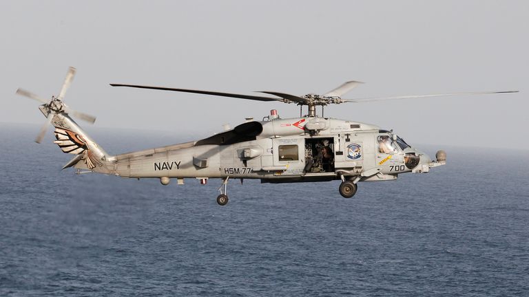 A Sikorsky SH-60 Seahawk helicopter flies near the Nimitz-class aircraft carrier USS Abraham Lincoln during a transit through the Strait of Hormuz, February 14, 2012