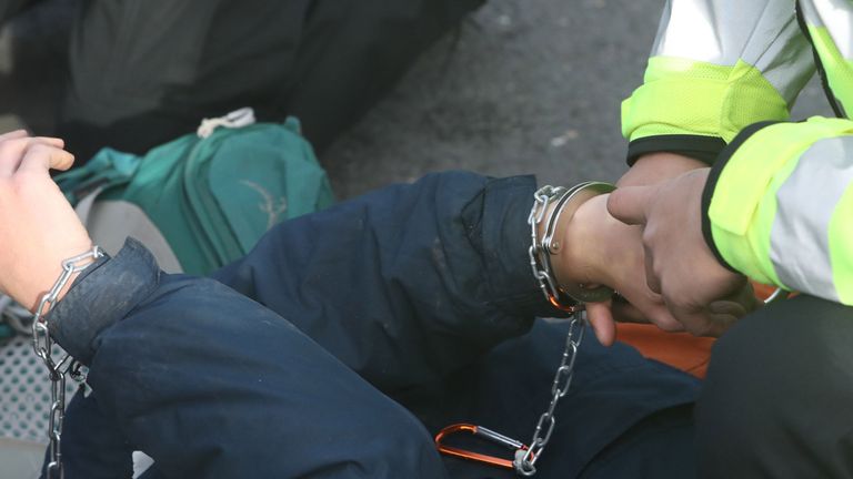 Police place handcuffs on a protestor from campaign group RisingUp! as they block the east ramp at Heathrow Airport, in protest over the development of a third runway. PRESS ASSOCIATION Photo. Picture date: Saturday November 19, 2016. See PA story PROTEST Heathrow. Photo credit should read: Steve Parsons/PA Wire
