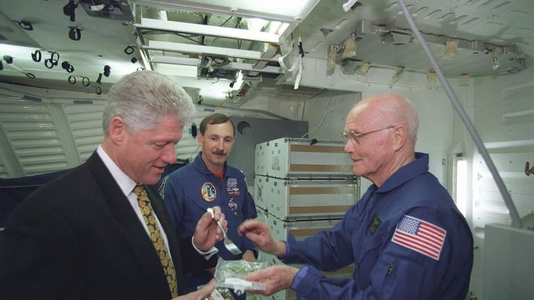 President Bill Clinton eats space food offered to him by John Glenn
