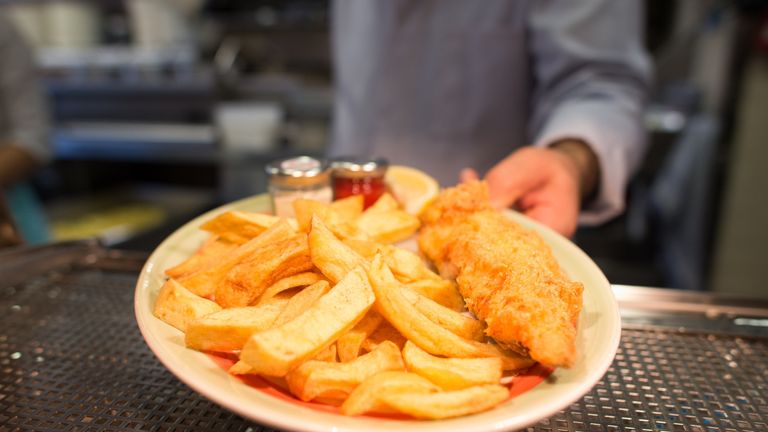 A chef poses with a plate of fish and chips at Poppies fish and chip restaurant in east London on January 26, 2015. Fish and chips, that a classic British dish, is a popular takeaway food in the UK with local media reporting that somewhere in the region of 250 million portions are served up annually
