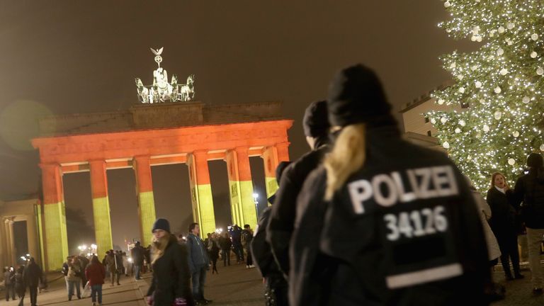 The Brandenburg Gate is illuminated as police walk past the day after a truck drove into a crowded Christmas market