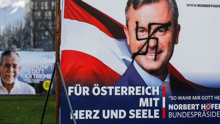 A vandalised poster of Norbert Hofer is seen next to a poster of rival Alexander Van der Bellen