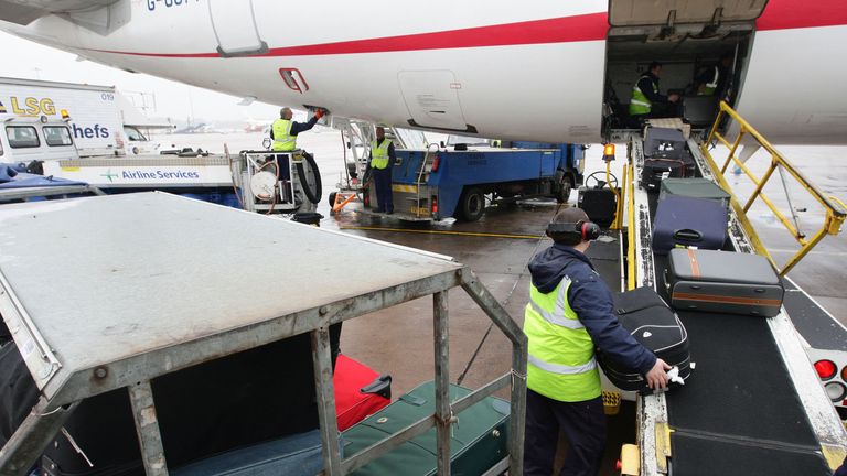 Baggage handlers unloading a plane at Manchester airport