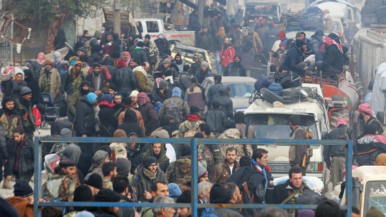 Rebel fighters and civilians gather as they wait to be evacuated from eastern Aleppo