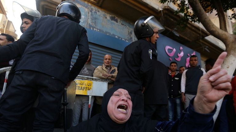 A woman cries while sitting in front of police officers in front of  the cathedral in Cairo after the bomb blast 