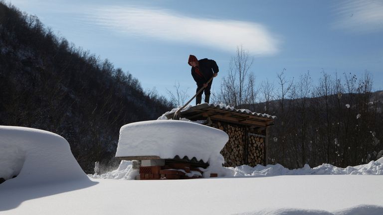 A man shovels snow off from a roof at around minus 26 degrees Celsius (minus 14.8 degrees Fahrenheit) in the village of Jezerc