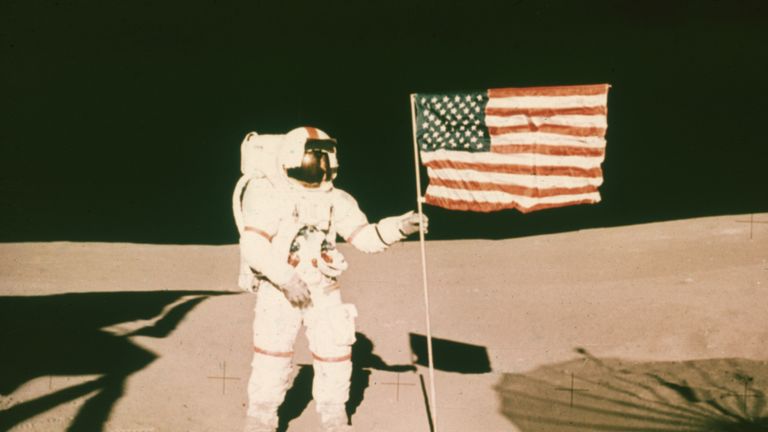 Astronaut Alan Shepard holds the pole of a US flag on the surface of the moon during the Apollo 14 mission