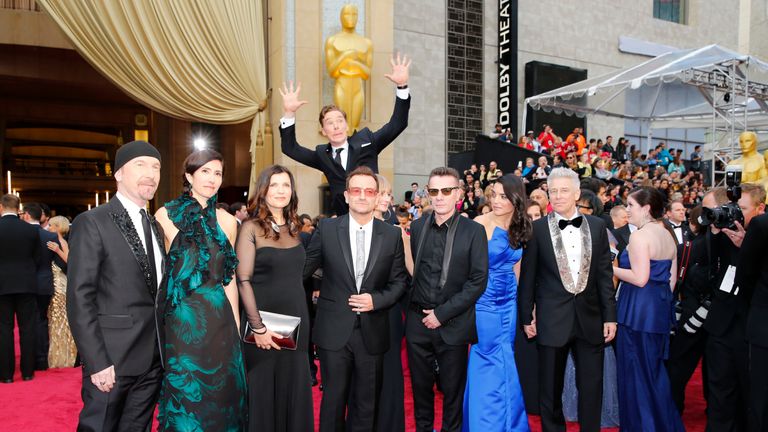 Actor Benedict Cumberbatch jumps behind U2 at the 86th Academy Awards in Hollywood, California March 2, 2014