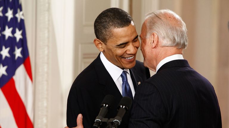 Joe Biden whispers to Barack Obama before he signs the Affordable Care Act