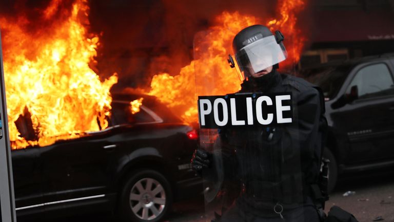 A limo is set on fire amid clashes between protesters and police officers