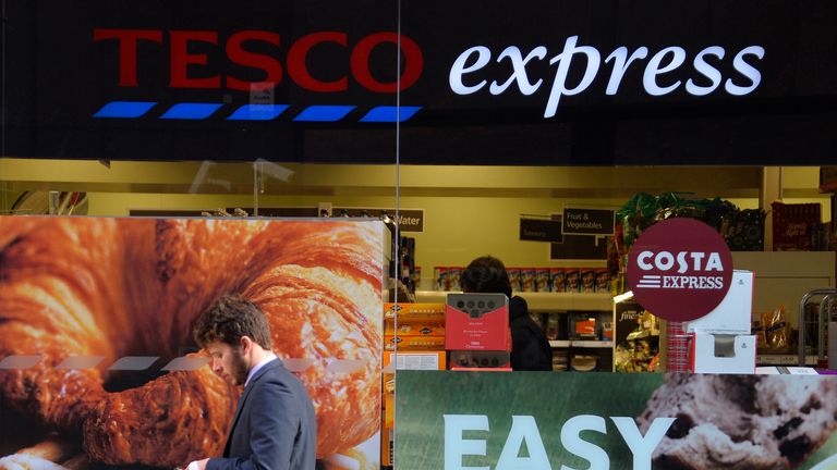 A customer passes a branch of the Tesco Express convenience store in central London December 2013