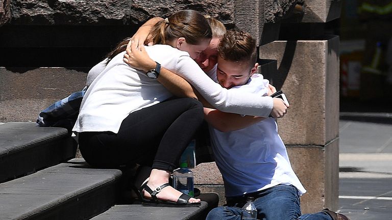 Pedestrians hug on the steps of a building near the crash