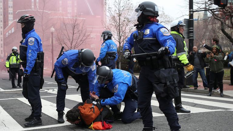 An protester is held to the floor and handcuffed by riot police