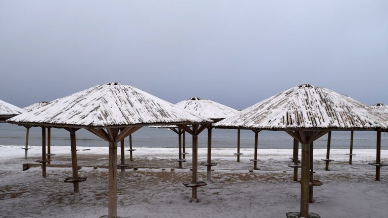 Beach umbrellas are covered with snow at the beach in the town of Artemida in Greece