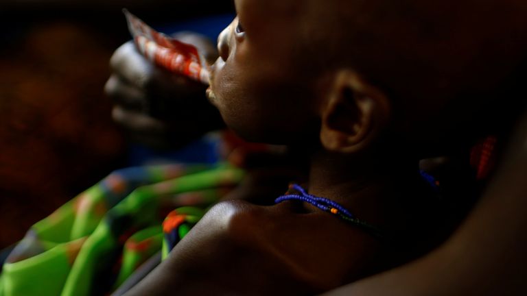 A mother feeds her child with a peanut-based paste for treatment of severe acute malnutrition