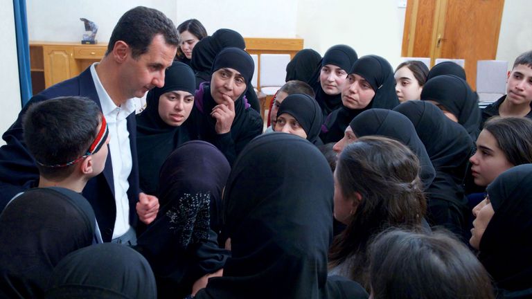 Mr Assad with women and children which he claims were freed after being held by opposition forces for more than three years