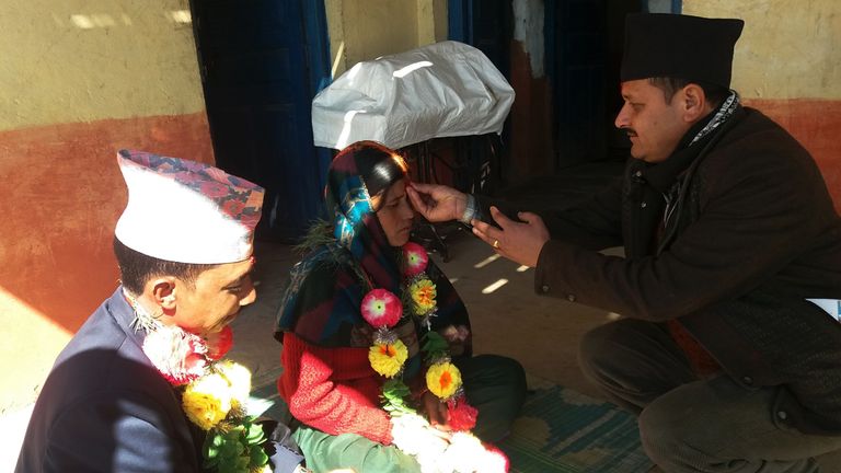 The pair are blessed by an official (R) during the ceremony