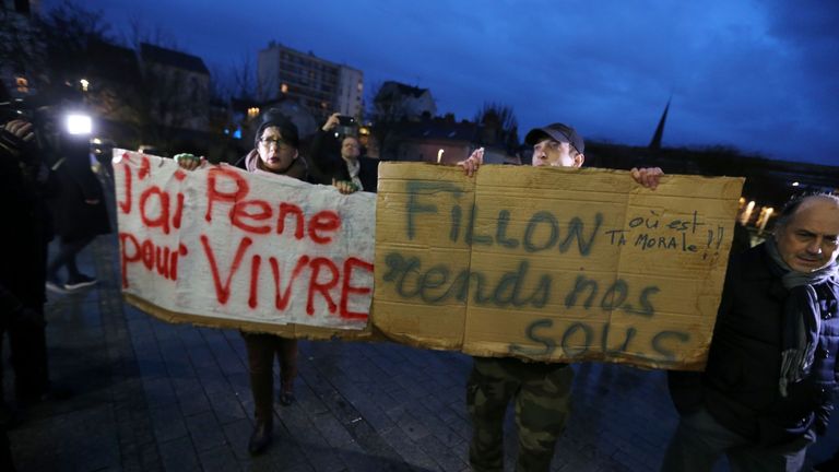 Protesters hold placards reading &#39;I have suffered to live&#39; (L) and &#39;Fillon, give us our money back - where is your morale&#39; during the visit of French presidential election candidate for the right-wing Les Republicains (LR) party Francois Fillon to the Mediatheque du Grand Troyes, in Troyes, northeastern France, on February 7, 2017