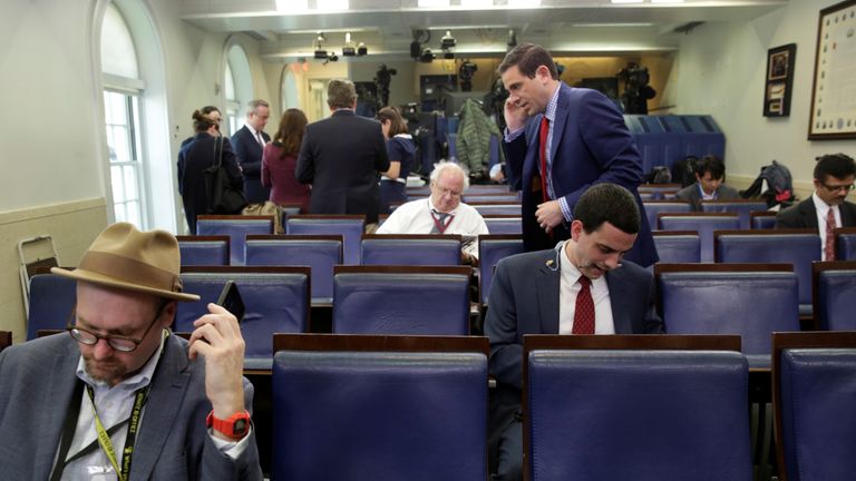 Glenn Thrush (L), chief White House political correspondent for the The New York Times, works in the briefing room after being excluded 