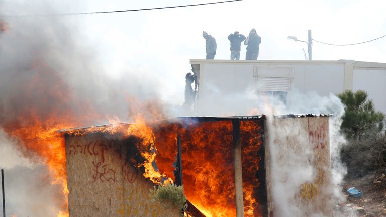 Protesters stand on a roof as a shed burns during an eviction by Israeli police of residents from the Israeli settler outpost of Amona in the West Bank
