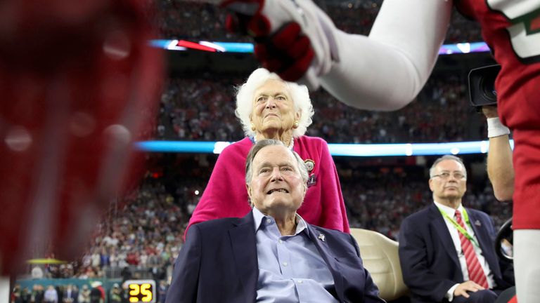 Former U.S. President George H.W. Bush watches the pre-game handshake as former first lady Barbara Bush looks on 