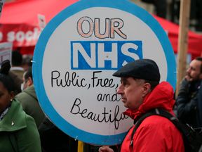 A protester holds a placard during a march against private companies' involvement in the National Health Service (NHS) and social care services provision and against cuts to NHS funding in central London on March 4, 2017. People gathered to demonstrate at the rally publicised by the People's Assembly Against Austerity to demand a fully and publicly funded NHS and social care service, returned fully to public ownership and provision and to say no to cuts in NHS funding