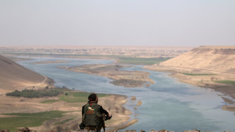 A Syrian Democratic Forces fighter rests while looking over the Euphrates River, north of Raqqa city