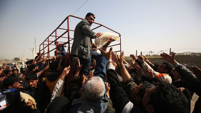 Displaced Iraqis receive food in Mosul's Mansour district on March 12, 2017, during an offensive by security forces to retake the western parts of the city from Islamic State (IS) group fighters