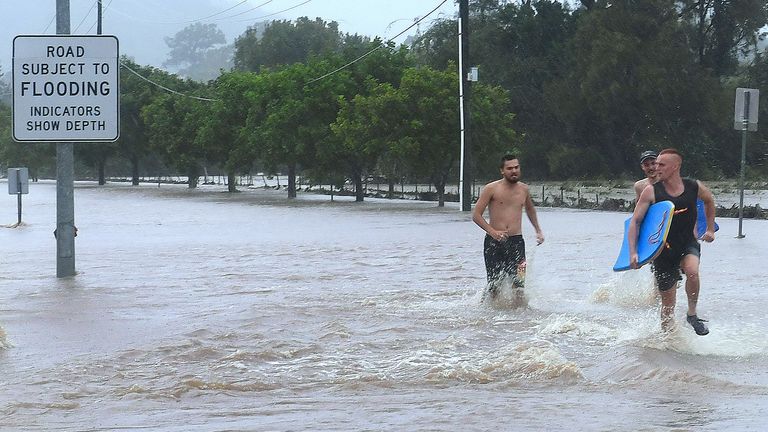 Locals run through floodwaters in the the Gold Coast suburb of Mudgeeraba in Queensland