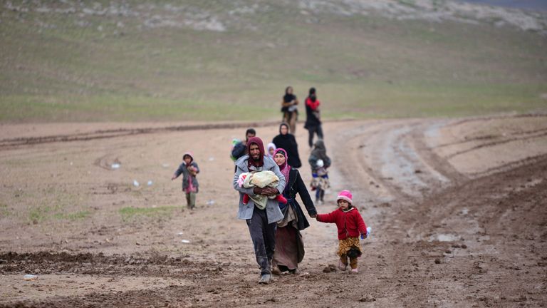 A displaced Iraqi man, who fled his home, carries his child during a battle between Iraqi forces and Islamic State militants, near Badush