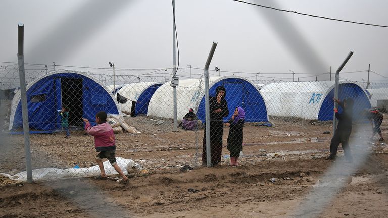 Displaced Iraqis stand near a fence at the Hamam al-Alil camp