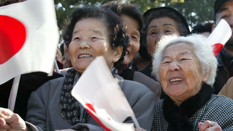 Elderly Japanese women wave national flags as Emperor Akihito makes a special appearance on his 69th birthday at the Imperial Palace in Tokyo, December 23, 2002