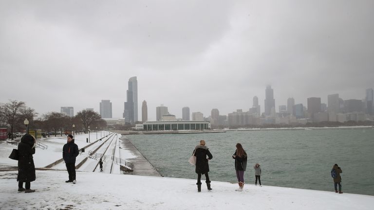 People walk along a snow-covered lakefront in downtown Chigaco