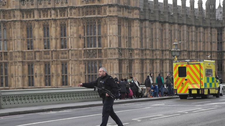 An armed police officer runs accross the road during an incident on Westminster Bridge 