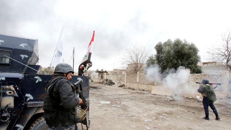 Federal police members fire their weapons during a battle against Islamic State militants