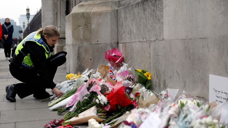 A police officer places a floral tribute near Westminster Bridge