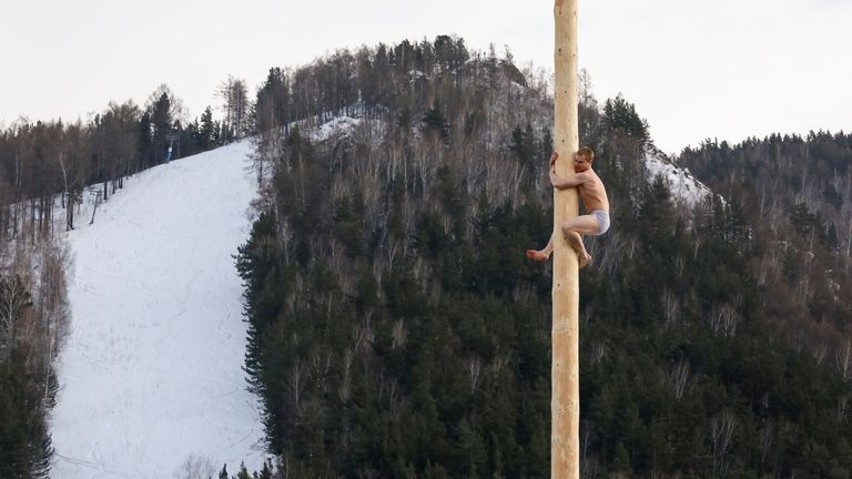 A man tries to get a prize from a pole during an celebration in Krasnoyarsk last month