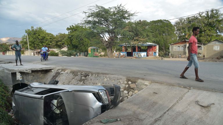 A car damaged by the speeding bus lies on the side of the road in Gonaives