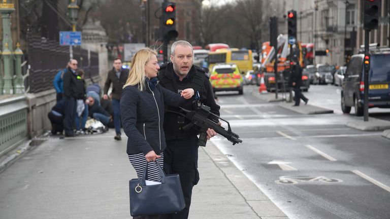 An armed police officer assists a woman after an incident on Westminster Bridge in London
