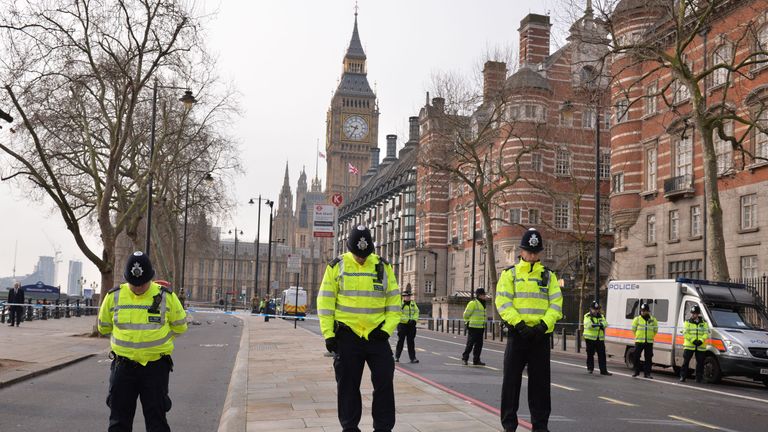 British police officers bow their heads as they stand near a police cordon 