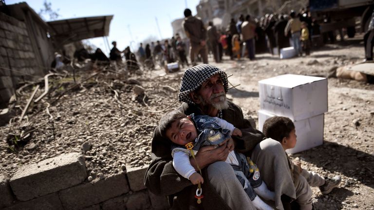 An elderly man holds a child in west Mosul, where Iraqi forces are trying to oust Islamic State