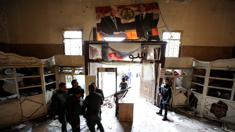 Security personnel stand at the damaged entrance to the Justice Palace in Damascus